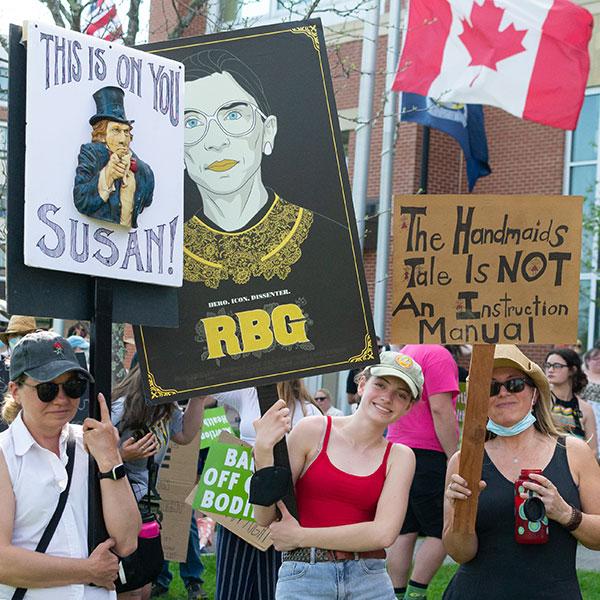 Three protesters holding signs supporting abortion